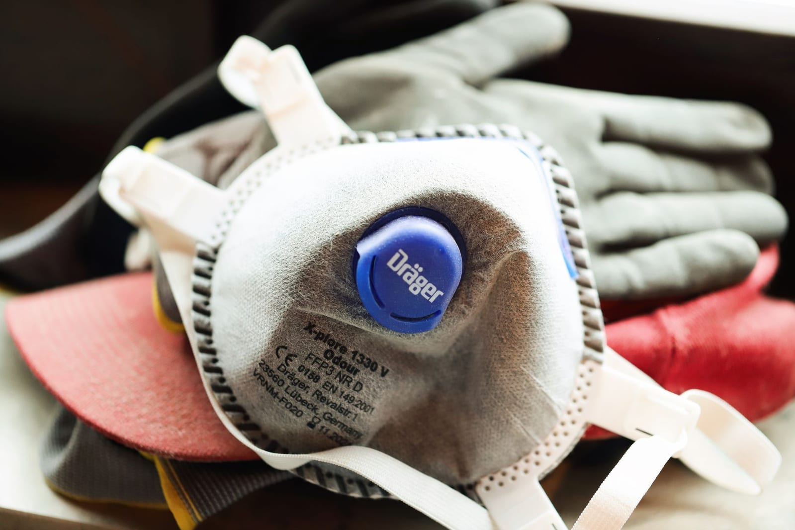 A close-up of a half-face respirator and work gloves used for chemical pest treatments